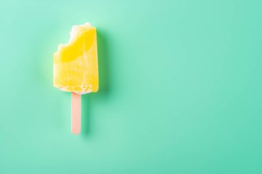 Açık yeşil arka planda yarısı yenmiş sarı buzlu şeker.