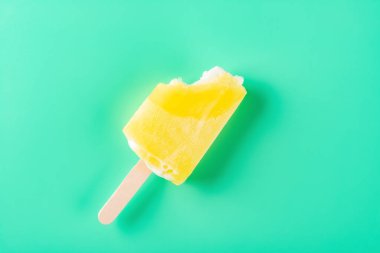 Açık yeşil zemin üzerinde birkaç ısırık olan sarı buzlu şeker.