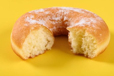 Sarı arka planda ısırık izleri olan donut.