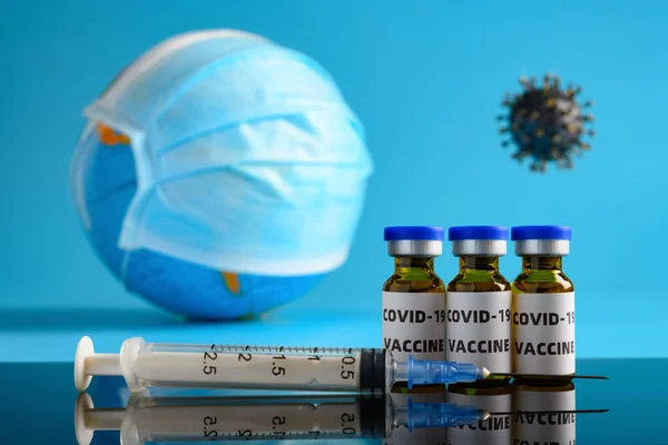 covid-19 vaccine and syringe with a globe wears mask and a coronavirus on background