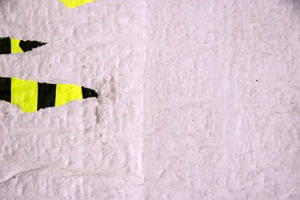 Beton duvardaki eski boyanın dokusu ve kağıt parçaları.