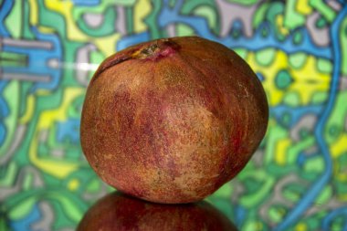 Pomegranate on a mirror surface close-up.