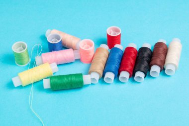 mavi arkaplanda renkli dikiş ipliği makaraları