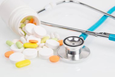 Beyaz şişede ilaç ve steteskop var.
