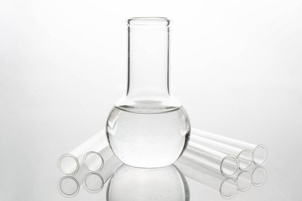 Medical test tube and glass flask on a white table