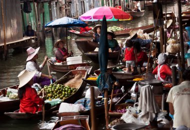 Damnoen Saduak, Tayland-9 Ağustos 2009: İnsanlar Bangkok yakınlarındaki yüzen bir pazarda teknesinden hediyeler satıyor