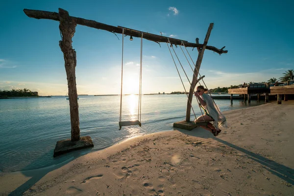 Vrouw maakt gebruik van een strand swing in de oceaan in een luxe resort in de — Stockfoto