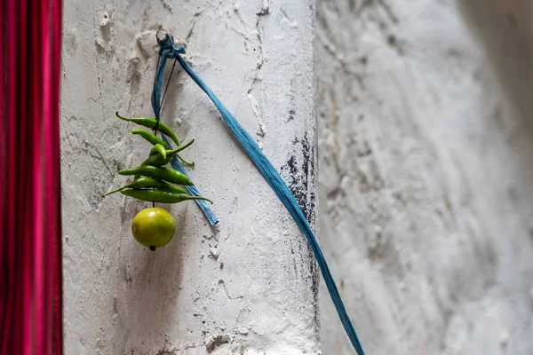 Green chillies with a lemon tied on a thread hanging on a doorwa