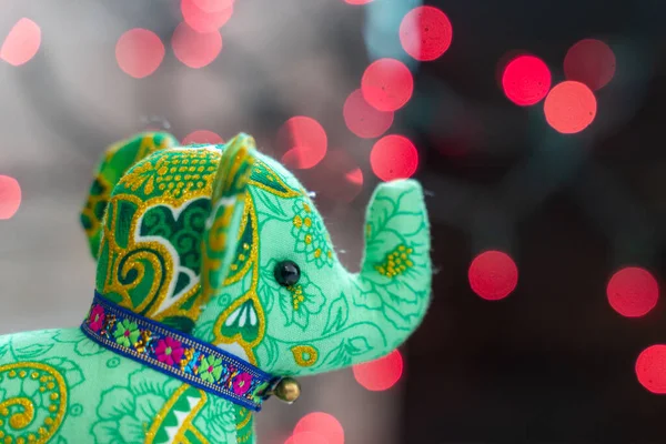 Adorable elefante verde peluche, delante de bokeh rojo backg — Foto de Stock