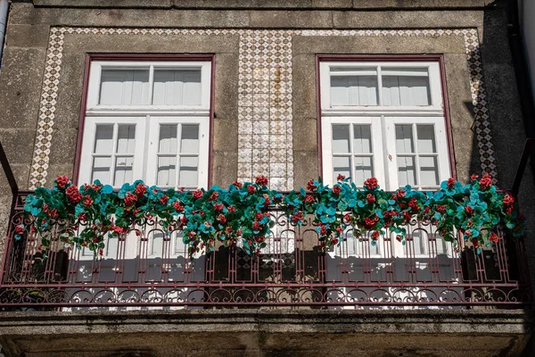 Söta fönster med kakel fasad och röda blommor på en utsmyckad balkon — Stockfoto