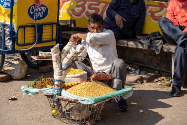 Rishikesh, Hindistan - 22 Şubat 2020: Hintli adam markette mısır, domates ve baklagillerden vegan sokak yemekleri yapıyor