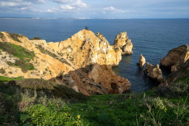 Lagos, Portekiz - 22 Ocak 2020: Heyecan arayan turistler Algarve 'deki manzaralı manzaraların dik uçurumlarında telefonla fotoğraf çekiyorlar