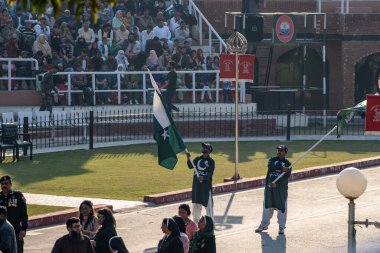 Wagah, Pakistan - Febuary 8, 2020: Two Pakistani men wave flags and hype up the crowd for the Wagah Border Closing Ceremony with India
