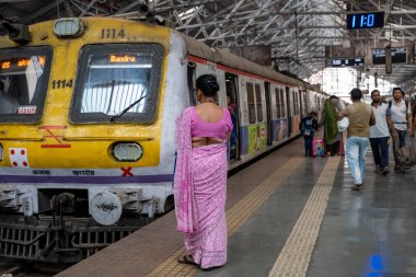 Mumbai, India - February 29, 2020: Indian woman wearing a sari waits for her train at Chatrapati Shivaji Terminus earlier known as Victoria Terminus in Mumbai, India