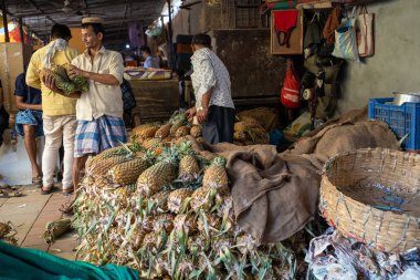 Mumbai, India - February 29, 2020: Vendors selling pineapple fruit hard at work in the Crawford Market, known for its fresh fruits and vegetables
