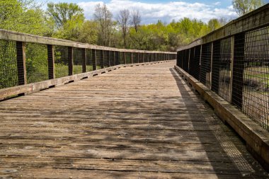 Maple Grove Minnesota 'da bir bahar günü Elm Creek Park Reserve' deki yaya köprüsünün alçak açılı görüntüsü.