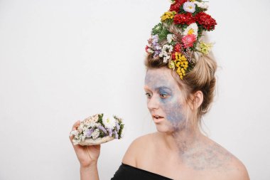 Onun kafası ve elleri üzerinde çiçekler olan bir genç kadın. Çiçekli bahar görüntü. Kız ve çiçek açan saç kesimi ve brokar yüzünde.