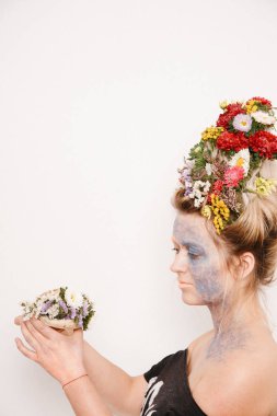 Onun kafası ve elleri üzerinde çiçekler olan bir genç kadın. Çiçekli bahar görüntü. Kız ve çiçek açan saç kesimi ve brokar yüzünde.