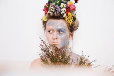 Onun kafası ve elleri üzerinde çiçekler olan bir genç kadın. Çiçekli bahar görüntü. Renkli bir bitki olan adam. Kız ve çiçek açan saç kesimi ve brokar yüzünde.