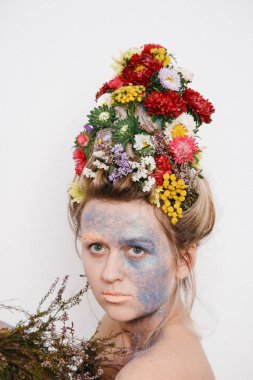 Onun kafası ve elleri üzerinde çiçekler olan bir genç kadın. Çiçekli bahar görüntü. Renkli bir bitki olan adam. Kız ve çiçek açan saç kesimi ve brokar yüzünde.