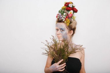 Onun kafası ve elleri üzerinde çiçekler olan bir genç kadın. Çiçekli bahar görüntü. Renkli bir bitki olan adam. Kız ve çiçek açan saç kesimi ve brokar yüzünde.