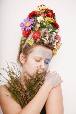 Onun kafası ve elleri üzerinde çiçekler olan bir genç kadın. Çiçekli bahar görüntü. Renkli bir bitki olan adam. Kız ve çiçek açan saç kesimi ve brokar yüzünde.