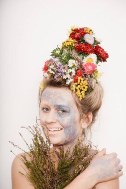 Onun kafası ve elleri üzerinde çiçekler olan bir genç kadın. Çiçekli bahar görüntü. Renkli bir bitki olan adam. Kız ve çiçek açan saç kesimi ve brokar yüzünde.