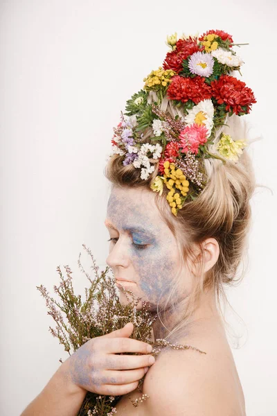 Onun kafası ve elleri üzerinde çiçekler olan bir genç kadın. Çiçekli bahar görüntü. Renkli bir bitki olan adam. Kız ve çiçek açan saç kesimi ve brokar yüzünde.