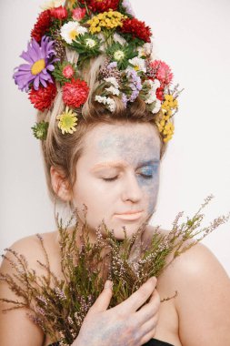 Onun kafası ve elleri üzerinde çiçekler olan bir genç kadın. Çiçekli bahar görüntü. Renkli bir bitki olan adam. Kız ve çiçek açan saç kesimi ve brokar yüzünde.