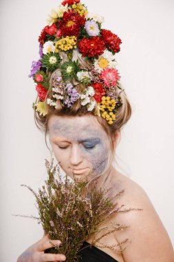 Onun kafası ve elleri üzerinde çiçekler olan bir genç kadın. Çiçekli bahar görüntü. Renkli bir bitki olan adam. Kız ve çiçek açan saç kesimi ve brokar yüzünde.