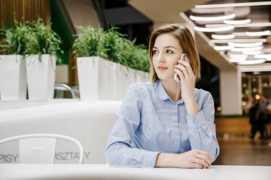 Telefon aracılığıyla bahseden bir genç kadın. Kız masada oturuyor ve bir sipariş yapar. İş kadını