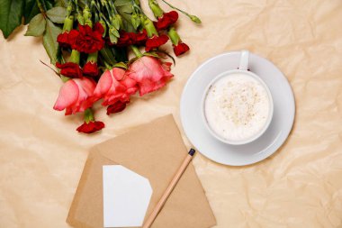 Bir fincan kahve, çiçekler ve bir zarf