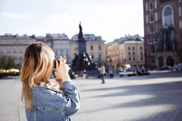 前往克拉科夫。女孩旅行和拍摄城市和它的街道。克拉科夫是波兰的一个欧洲城市。一个年轻的女士在市场中间和在老城市. — 图库照片
