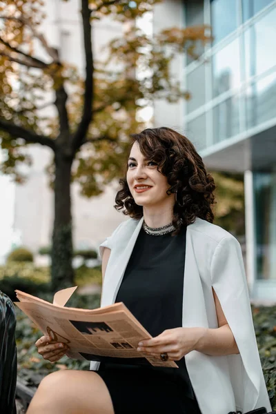 Stylish woman reading a newspaper. Successful girl with a notebook. Business woman. Stylish girl with a notebook. The lady is smiling.