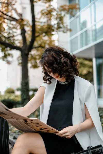 Stylish woman reading a newspaper. Successful girl with a notebook. Business woman. Stylish girl with a notebook. The lady is smiling.