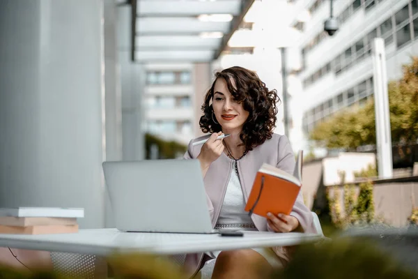 Stylish woman reading a newspaper. Successful girl with a notebook. Business woman. Stylish girl with a notebook. The lady is smiling.