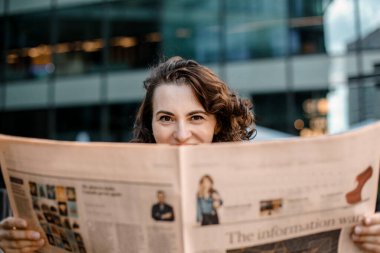 Genç bir kadın gazete ve kitap okuyor, gülümsüyor. Varşova, Polonya