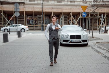 Dışarıda çalışan mutlu iş adamları, girişimci ve iş özgürlüğü iletişim teknolojisi. Büyük bir şehirde kulaklık takmış bir adam telefon tutuyor. Elini cebine sokuyor.