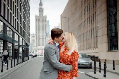 Büyük şehirde turist bir çift. Yanında kız olan adam sarılıyor ve mutlu. Kırmızı elbiseli kız oğlanı öpüyor. Kulaklıklı adam.