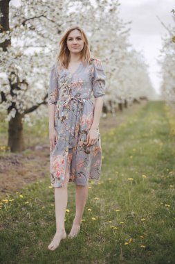 Çiçek açan bahçede bir kız. Bahar bahçesi. Çiçekli ağaçların arasında neşeli bir kız. Kiraz çiçeği.