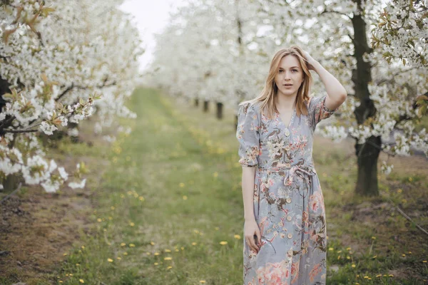 Meisje in een bloeiende tuin. Voorjaarstuin. Vrolijk meisje tussen bomen met bloemen. Kersenbloesem — Stockfoto