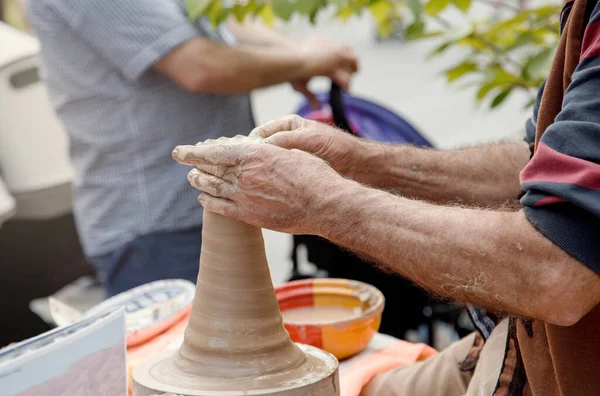 Closeup image ceramist man hands. Modeling clay. Handmade pot from clay. partial view of potter working on pottery wheel at workshop.