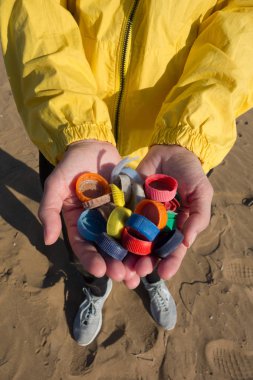 Plajda toplanan plastik tıkaçlarla dolu eller. Okyanus plastik kirliliği kavramı.