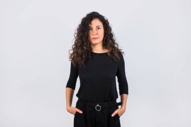 Kıvırcık saçlı esmer kadın ve siyah gömlek gülümseyen kameraya bakıyor..