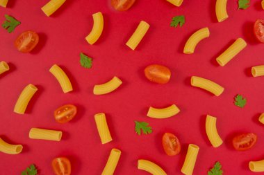 Kırmızı arka planda makarna, domates ve maydanoz deseni. İtalyan yemeği. Makarna kompozisyonu. Düz uzanma düzeni.