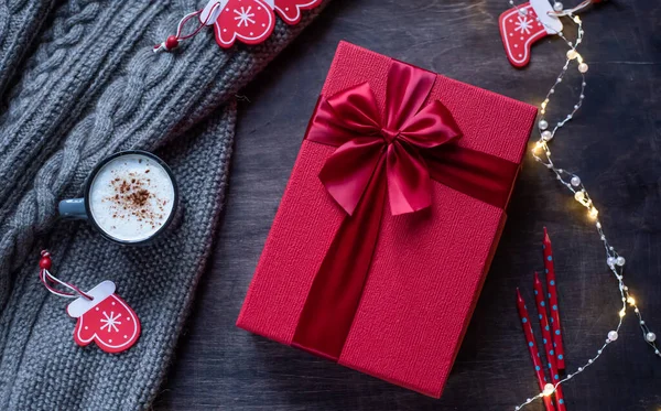 Caja de regalo roja con lazo sobre fondo de madera oscura. Guirnalda festiva con luces . — Foto de Stock