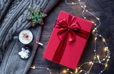 Siyah ahşap kaplamalı kırmızı hediye kutusu. Işıklı neşeli bir çelenk.