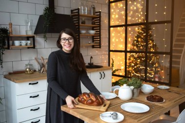 Genç bir kadın Noel için hazırlanıyor. Ev hanımı mutfakta..