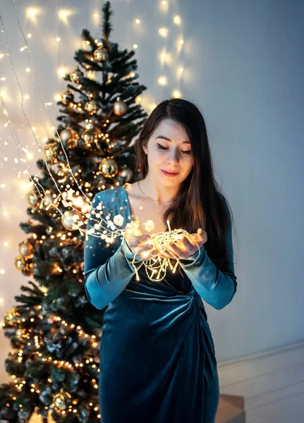Photo de Noël. Une jeune femme avec des lumières dans les mains . — Photo