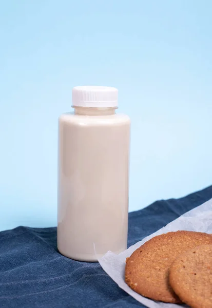 Bottle with vegetable coconut milk on a blue background. Homemade cookies on baking paper.